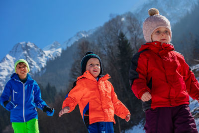 Rear view of friends standing against snowcapped mountain