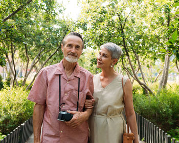 Portrait of smiling couple standing against trees