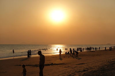 Silhouette people on beach against sky during sunset