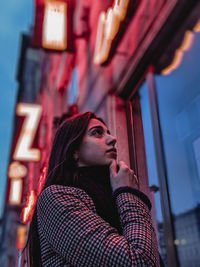 Low angle portrait of young woman looking away in city