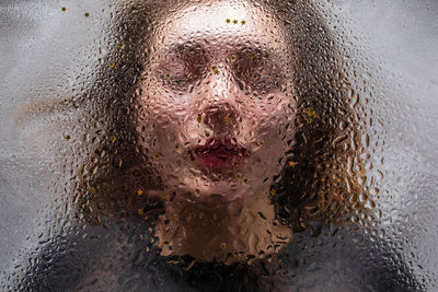 Close-up of woman seen through wet glass