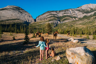 Children standing on landscape against mountains