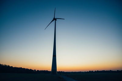 Low angle view of wind turbine against sky during sunset