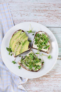 Sandwich rye bread with cereals, cream cheese, avocado and sprouted radish sprouts  microgreen