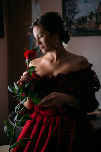 Beautiful woman in vintage 1800s early 1900s clothing red dress in old interior. historical dresses