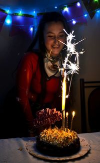 Young woman in front of illuminated cake