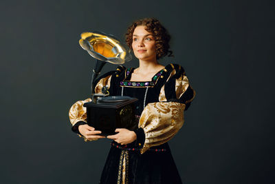 Portrait of young woman standing against black background