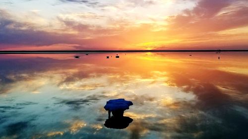 Silhouette man on sea against sky during sunset