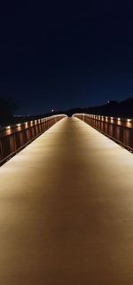 Illuminated bridge against clear sky at night