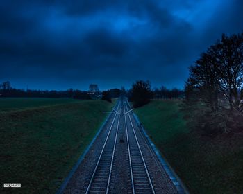 Railroad tracks on field against sky at dusk