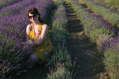 Portrait of woman wearing sunglasses crouching midst lavenders