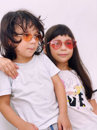 Siblings wearing sunglasses against wall