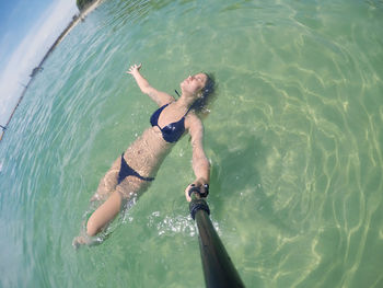 High angle view of young woman wearing bikini swimming in sea