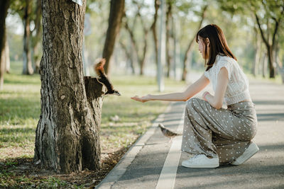 Side view of woman sitting on tree trunk
