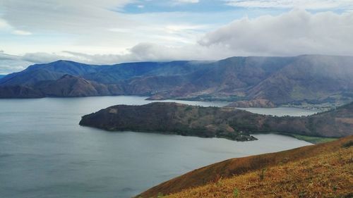 Scenic view of river by mountains against sky