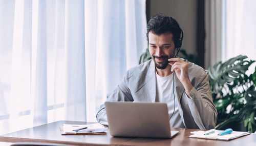 Young man using mobile phone while sitting on table