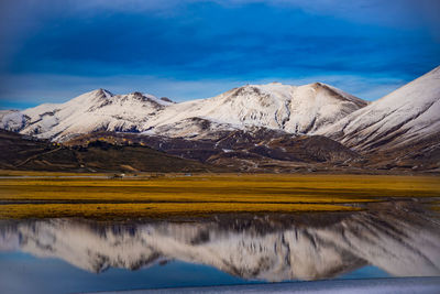 Scenic view of snowcapped mountains against blue sky