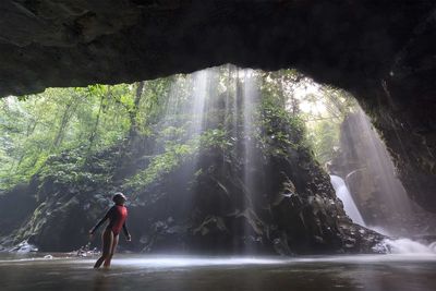 Rear view of man surfing on rock