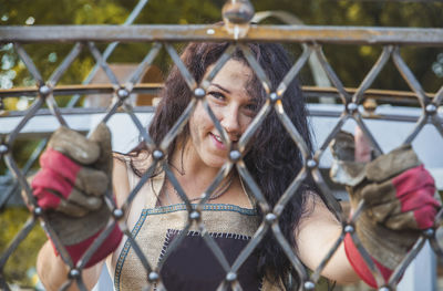 Portrait of young woman standing by railing