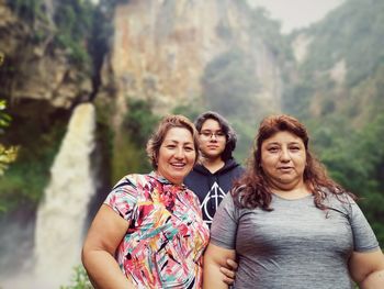 Portrait of smiling women standing against waterfall