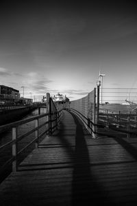 Empty footbridge against sky in city