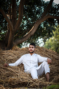 Portrait of young man sitting on field