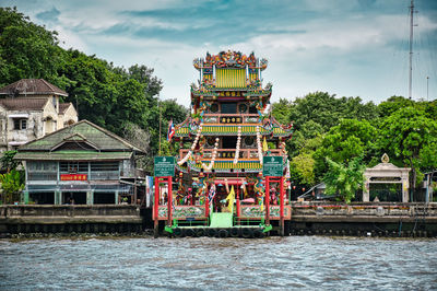 Traditional building by river against sky