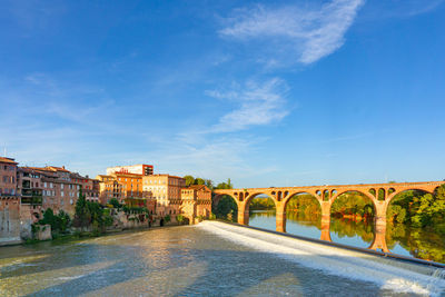 Arch bridge over river against blue sky