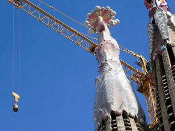 Low angle view of crane at sagrada familia during renovation against sky