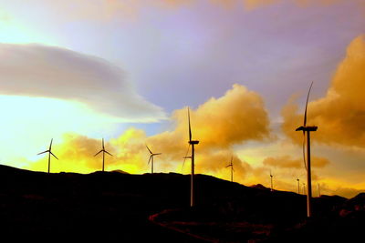 Low angle view of wind turbines at sunset