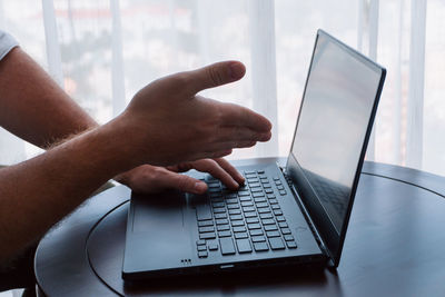 Cropped hands using laptop on table