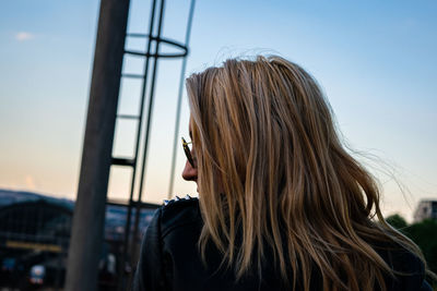 Young woman with blond hair against sky during sunset