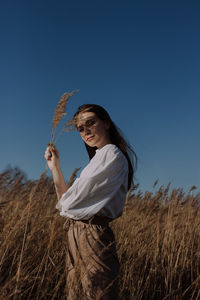 Low angle view of smiling woman standing on field against clear sky