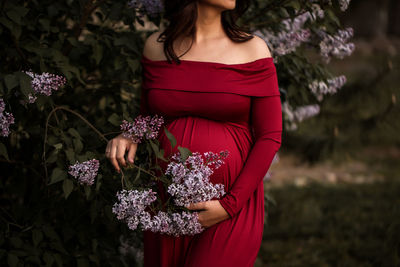 Midsection of woman standing against red wall