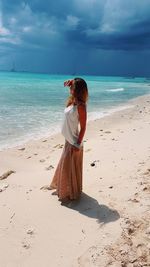 Rear view of woman standing on beach against sky