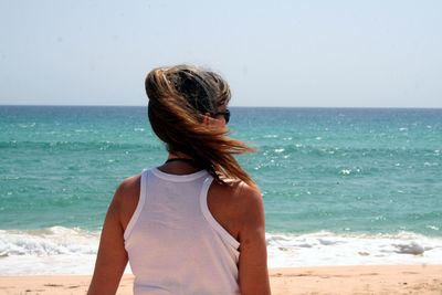 Rear view of woman at beach on sunny day