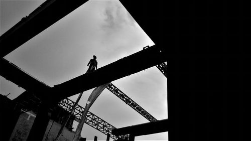 Low angle view of silhouette man working against sky