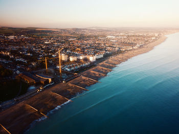 High angle drone view of worthing sea front with city scape and beach at sunset