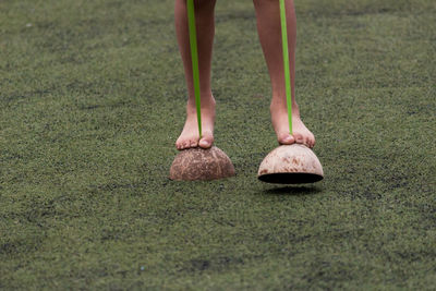 Low section of child walking on coconut shells at field