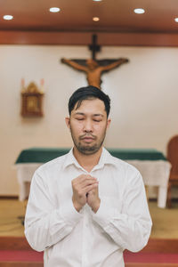 A christian man is sitting and praying with humble heart in the church.