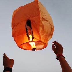 Low angle view of person holding lantern against sky