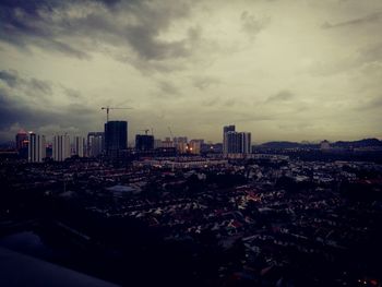 Aerial view of city lit up against cloudy sky