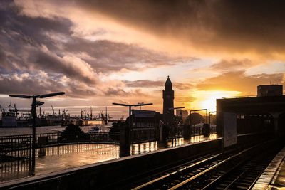 Railroad tracks in city against sky during sunset