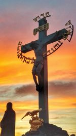 Statue of cross against sky during sunset
