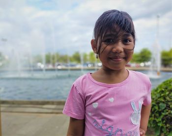 Portrait of smiling girl standing against water