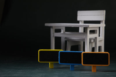 Empty chairs and table against black background