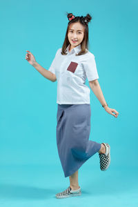 Portrait of young woman standing against blue background