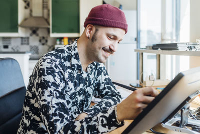 Young man using mobile phone while sitting on table