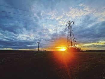 Low angle view of electricity pylon on field against sky