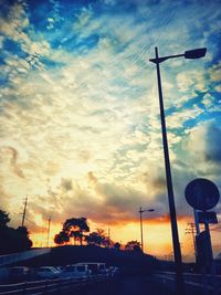 Vehicles on road against dramatic sky